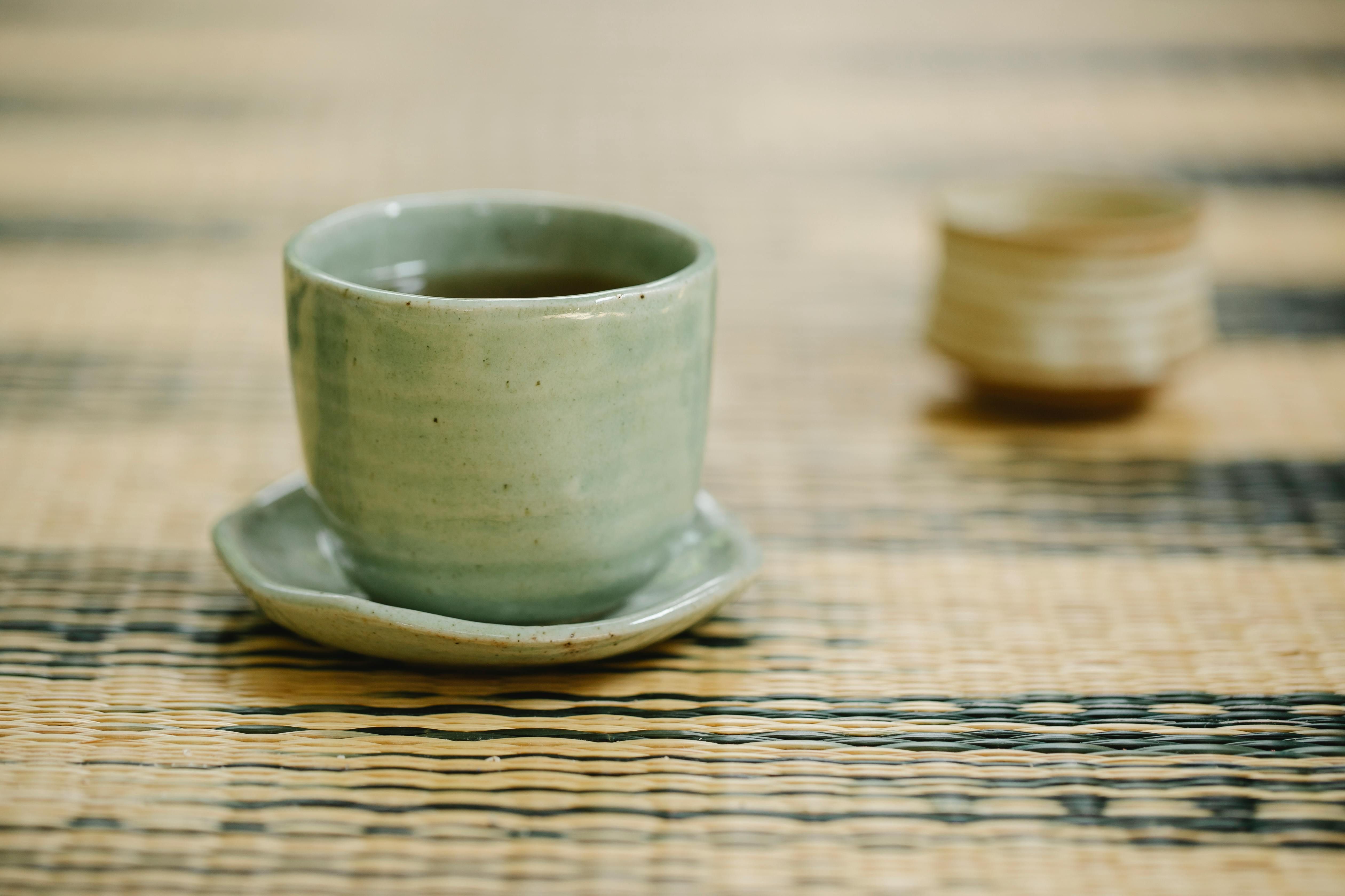 A elegant ceramic teacup filled with fresh, rich black tea sitting on a rustic wooden surface - the perfect morning ritual while intermittent fasting