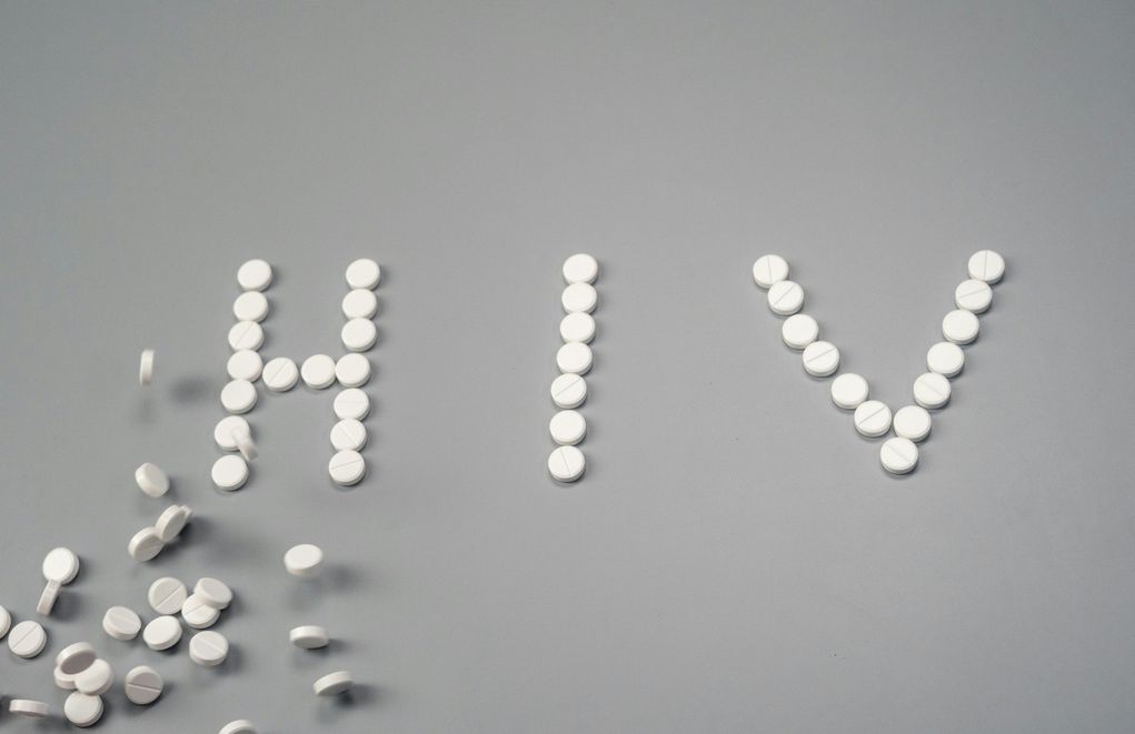 Pills spilling out of an HIV medication bottle next to an intermittent fasting app on a phone, representing the intersection of HIV treatment and fasting.