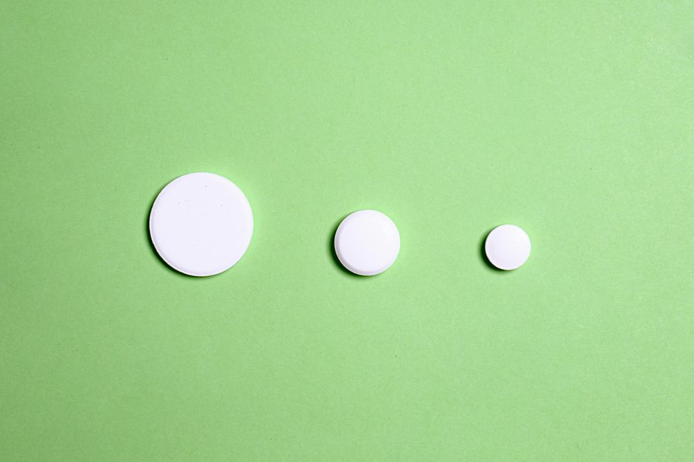 Various sleep medication pills scattered next to a smartphone displaying an intermittent fasting app, illustrating the question of whether sleep meds interfere with fasting.