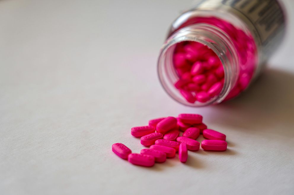 A bottle of mood stabilizer pills beside an intermittent fasting tracking app, representing the integration of mental health treatment and fasting