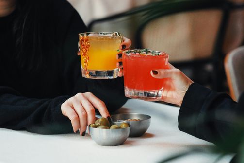 A woman preparing a refreshing low-sugar cocktail with fresh fruit and herbs, prioritizing health and wellness while enjoying social drinking.