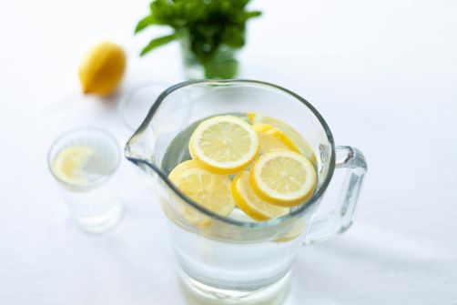 A woman preparing a pitcher of infused water with fresh fruit and herbs, making hydration both healthy and enjoyable.