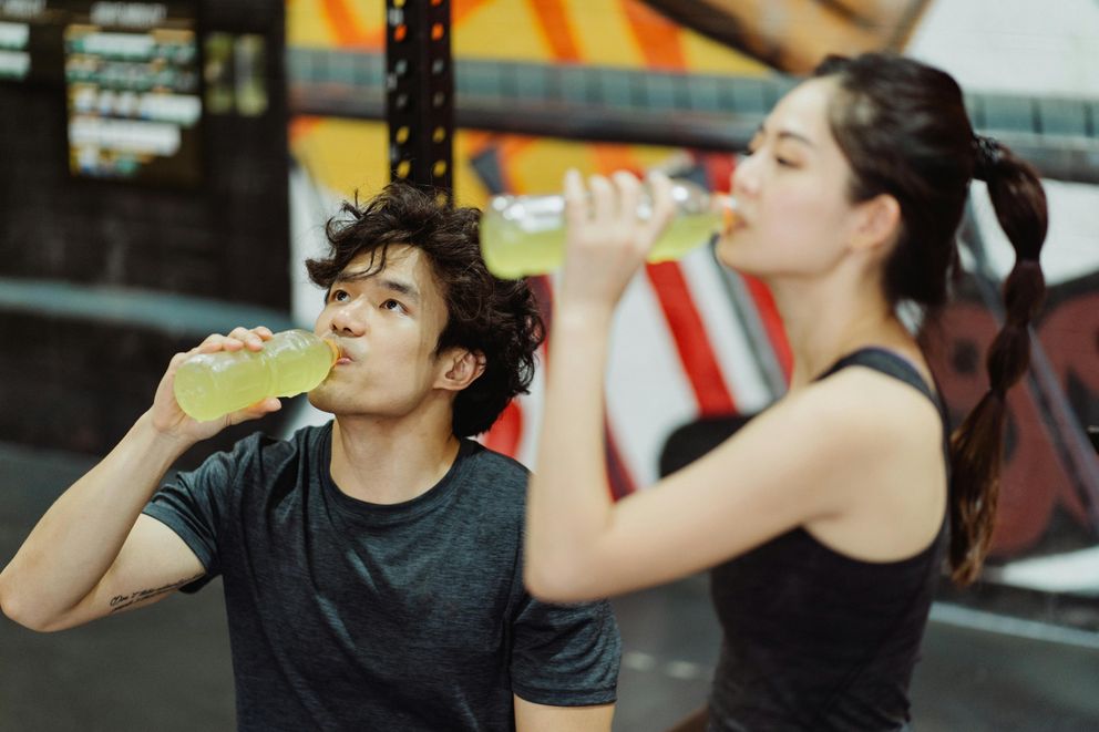 A woman replenishing electrolytes naturally with a drink after a workout, supporting hydration and muscle recovery.