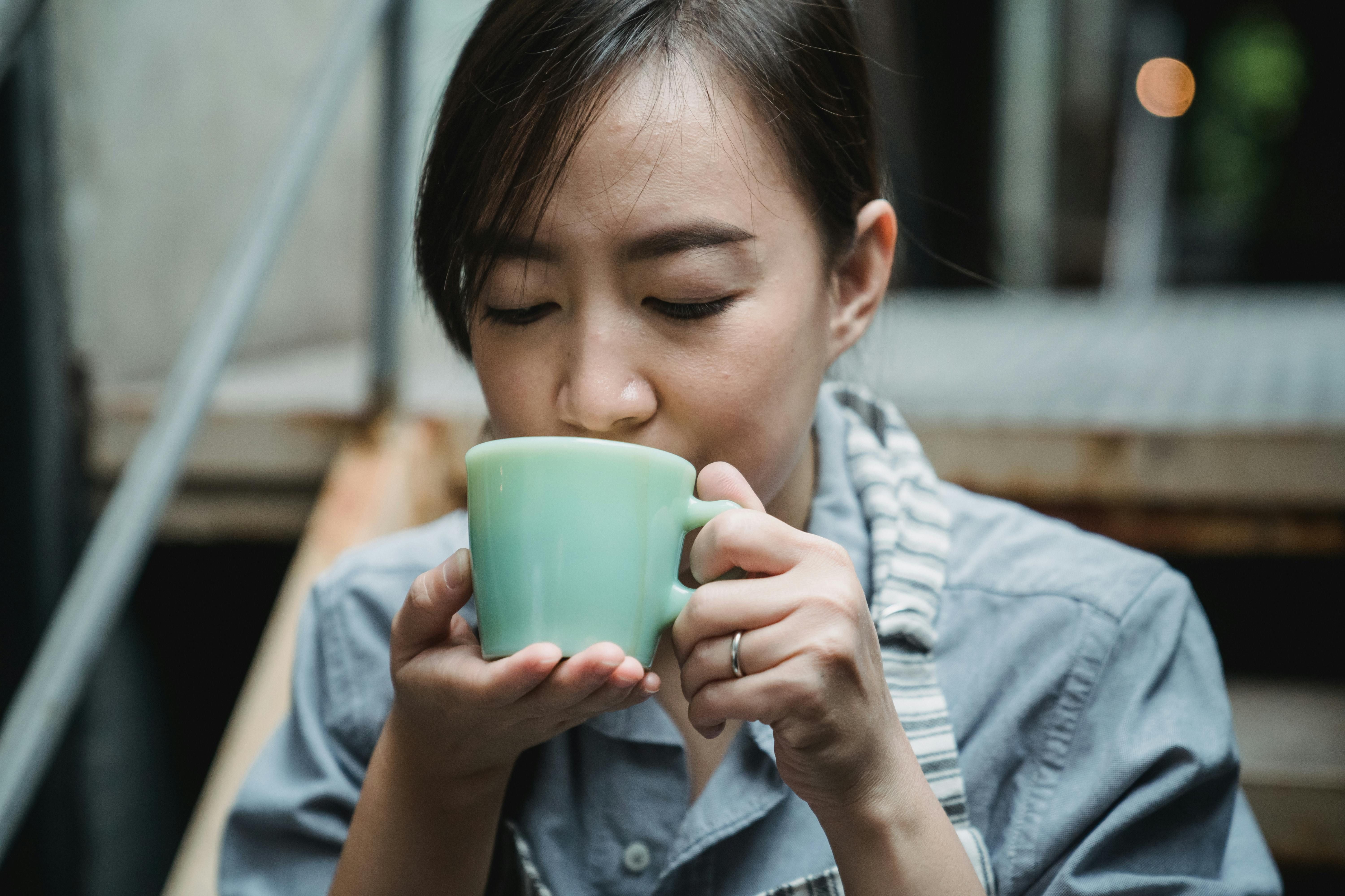 A woman drinking herbal tea, enjoying its calming benefits for stress relief and overall wellness.