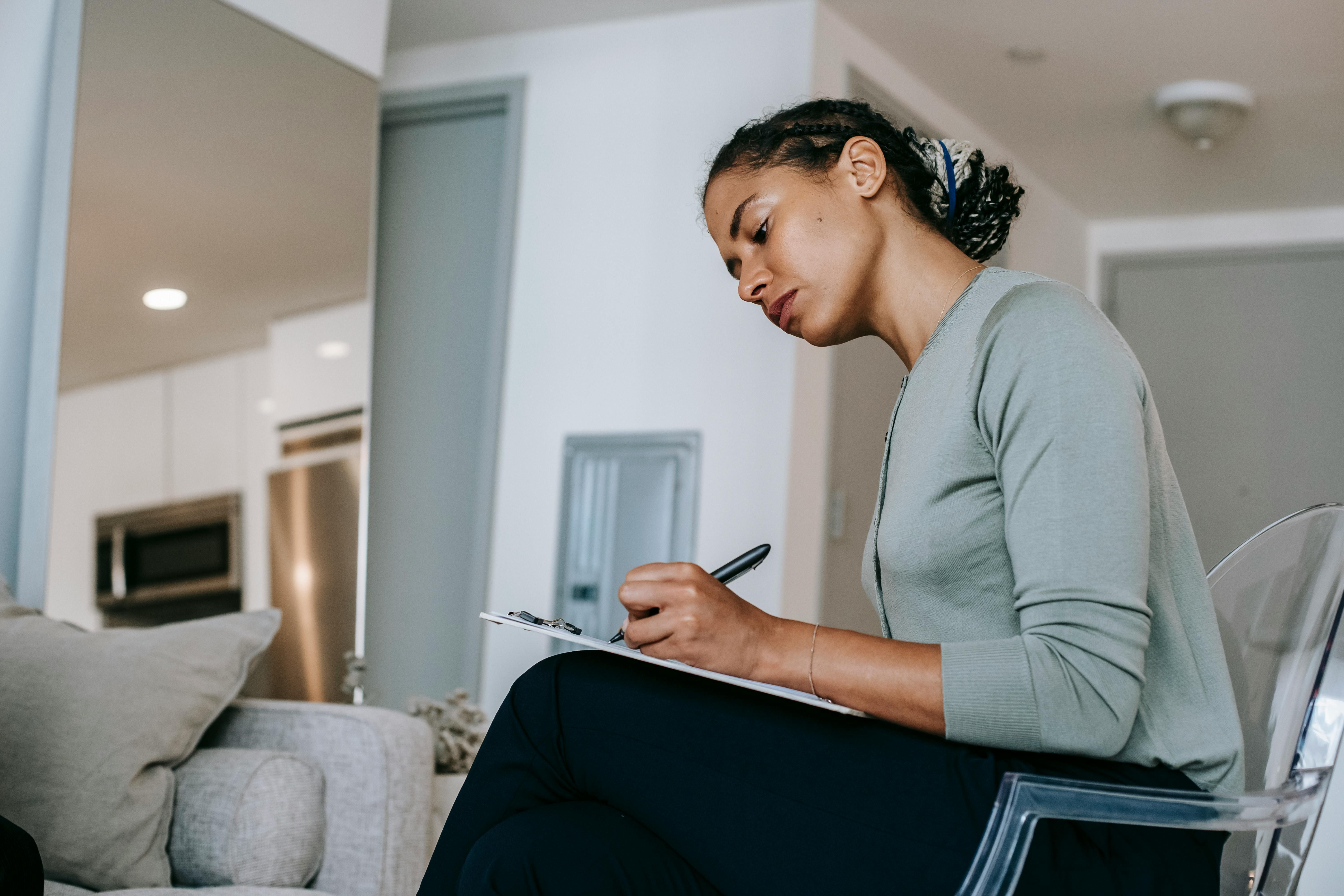 A woman journaling her thoughts to overcome imposter syndrome, reflecting on her accomplishments and self-worth.