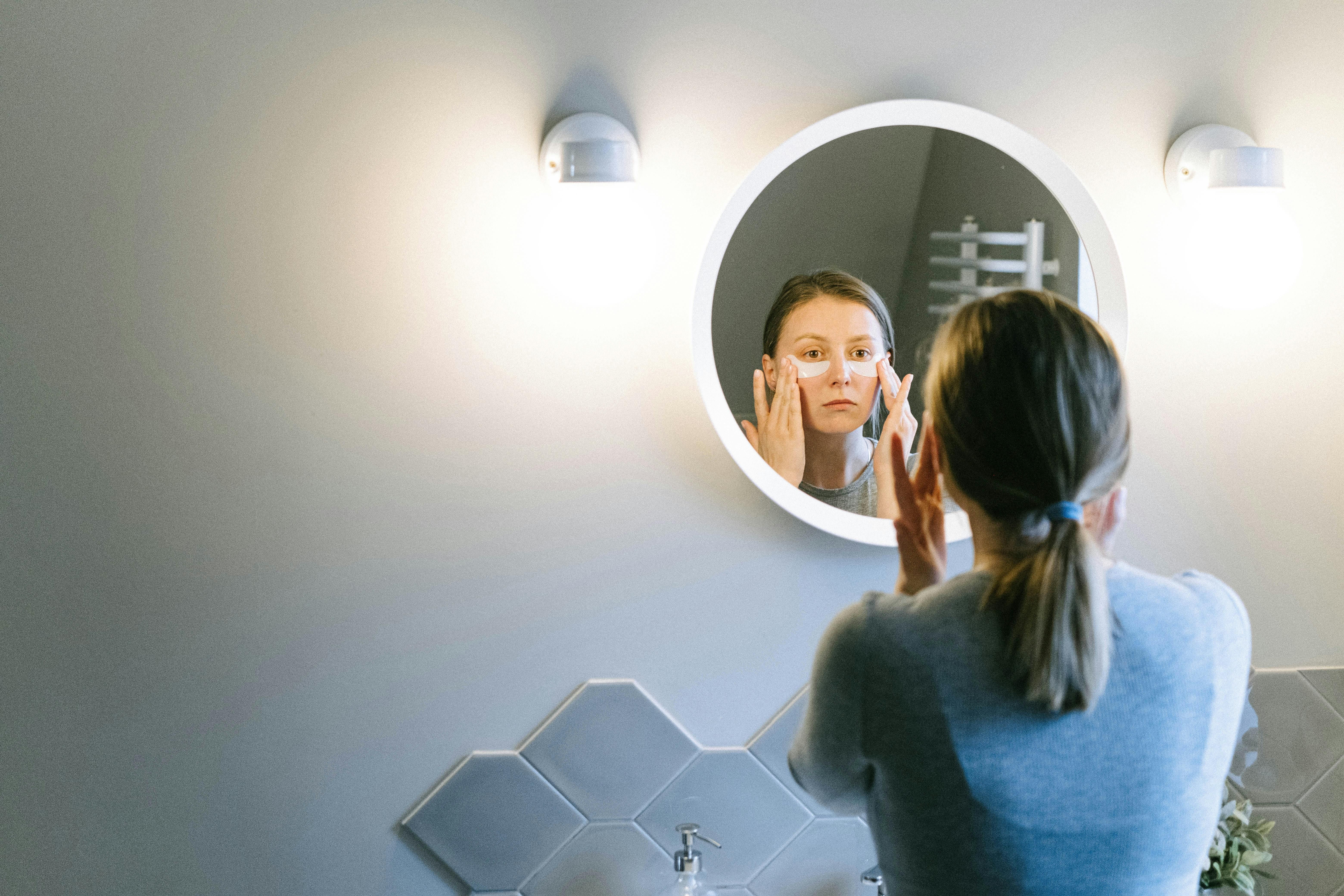 A woman applying night cream and under-eye patches as part of her nighttime skincare routine to rejuvenate and hydrate her skin before sleep.