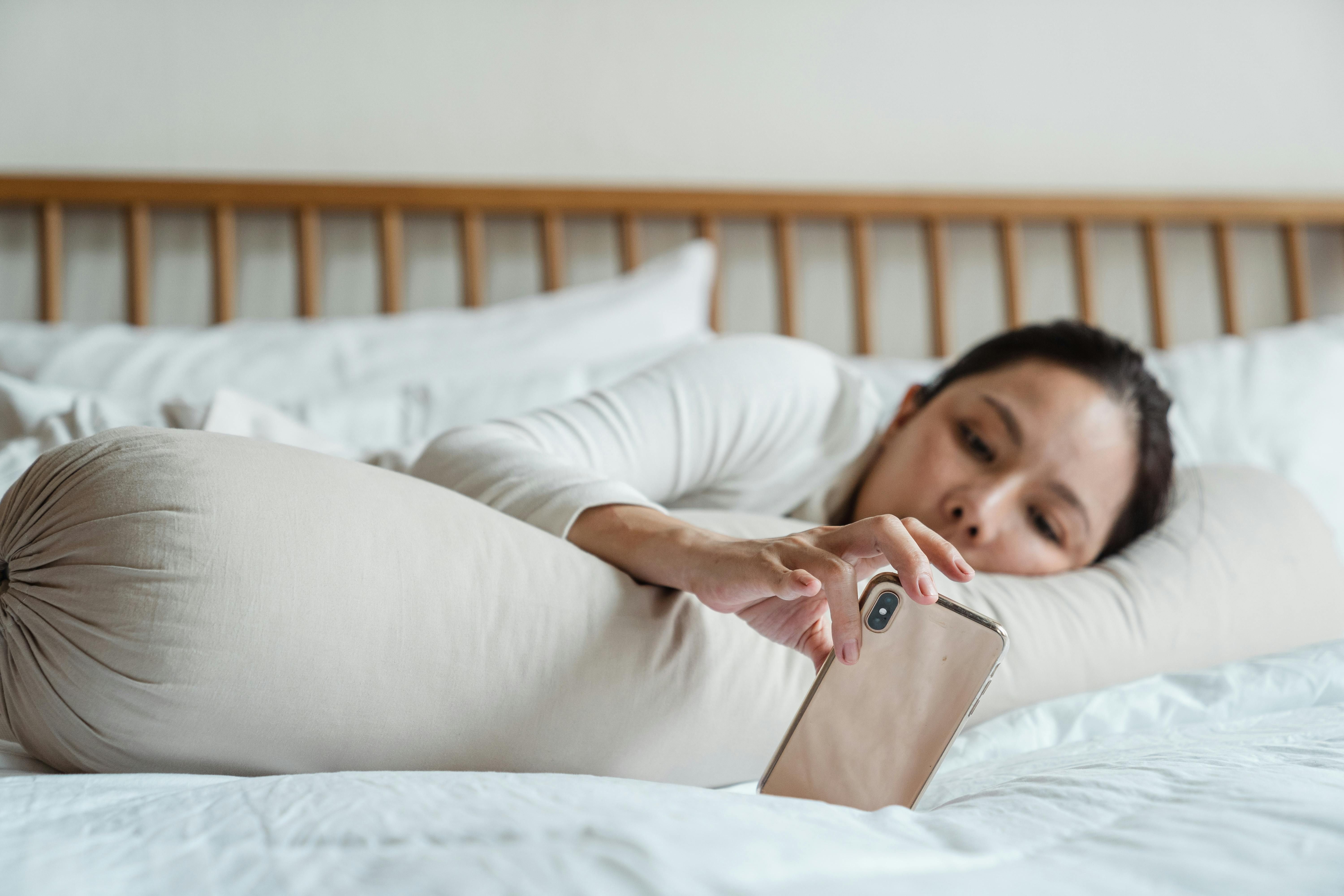 A woman turning off her smartphone before going to sleep, creating a tech-free environment for better rest.