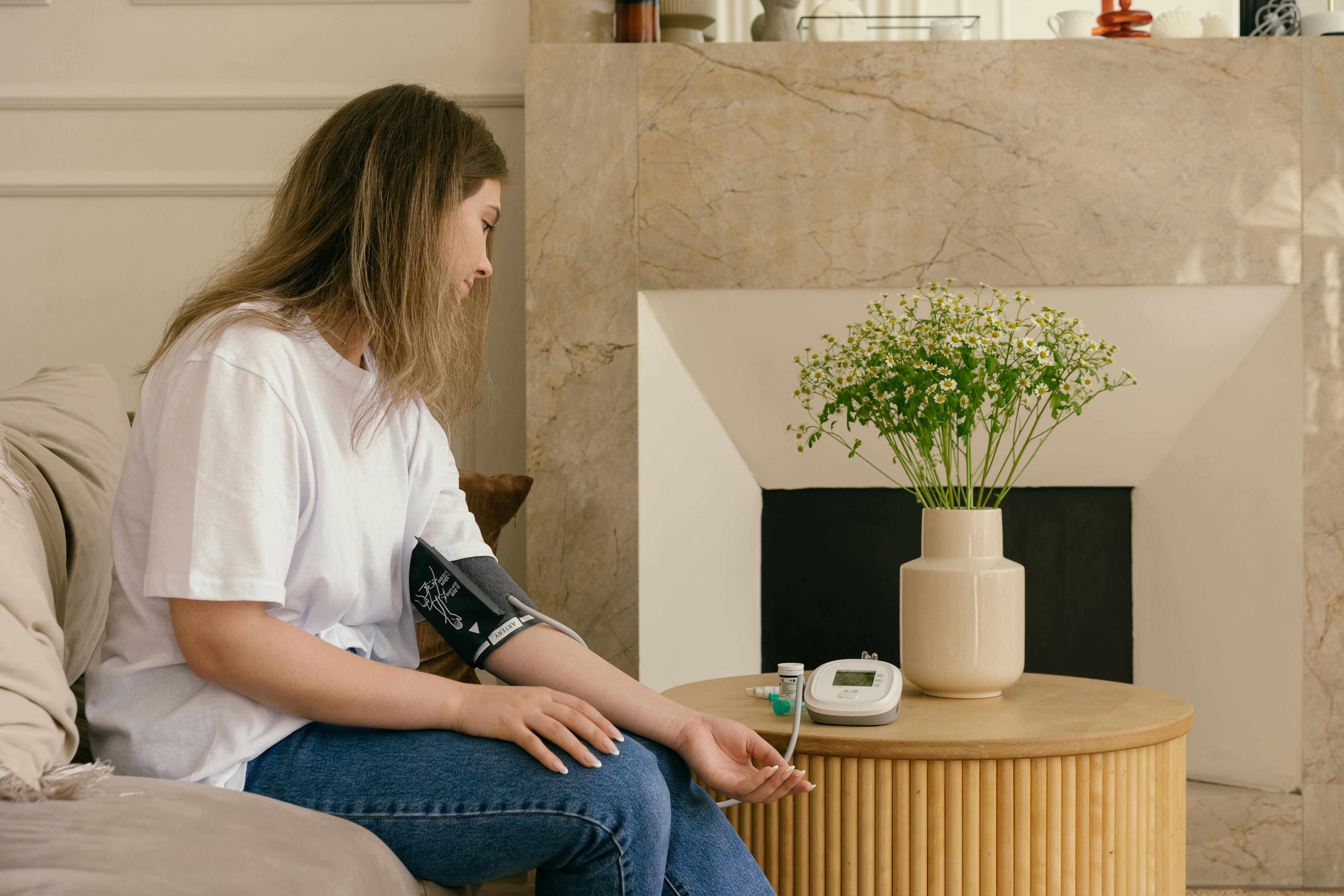 A woman measuring her blood pressure at home, ensuring healthy blood pressure levels.