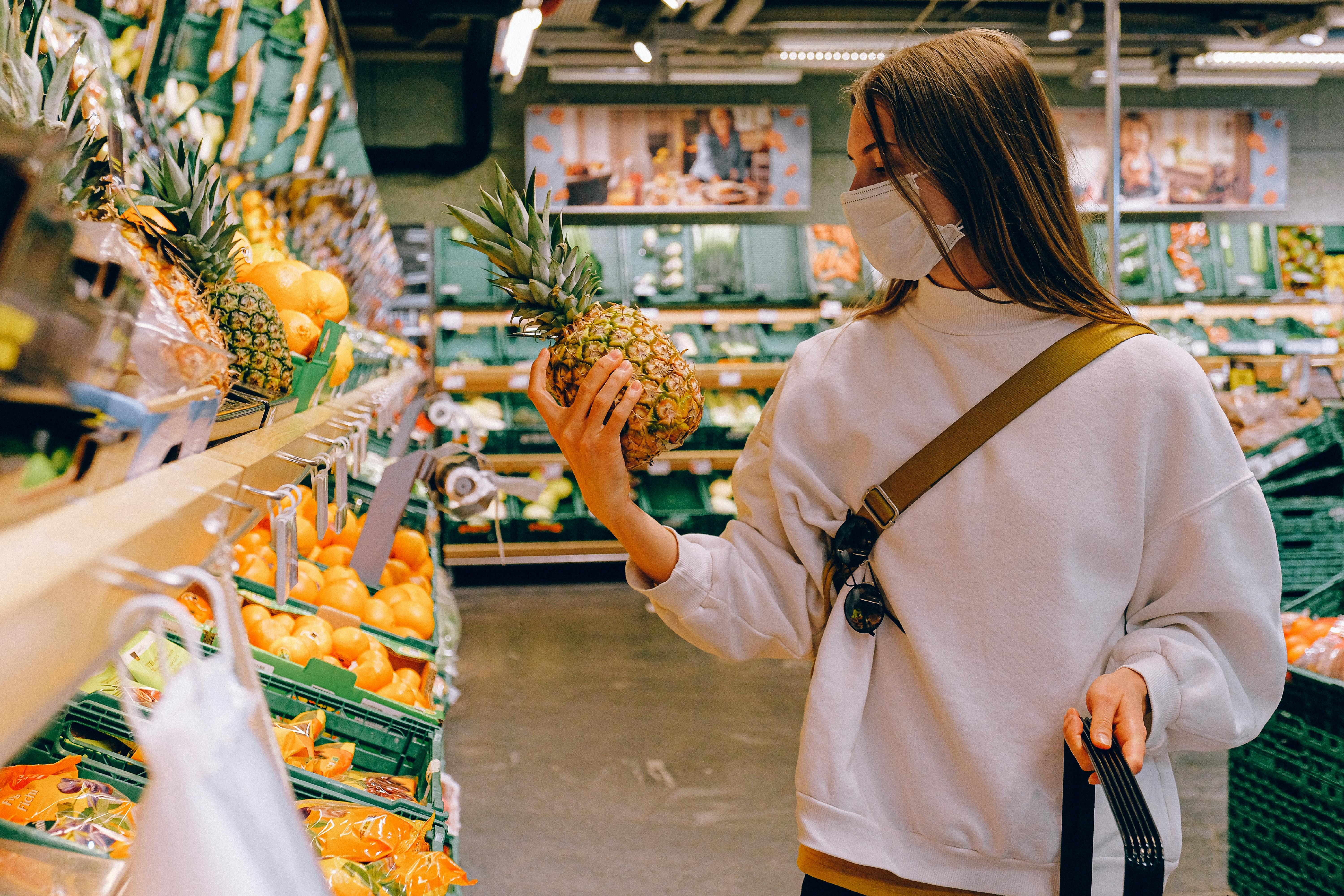 A woman with ADHD thoughtfully choosing nutrient-dense foods at the supermarket to support focus and manage symptoms.