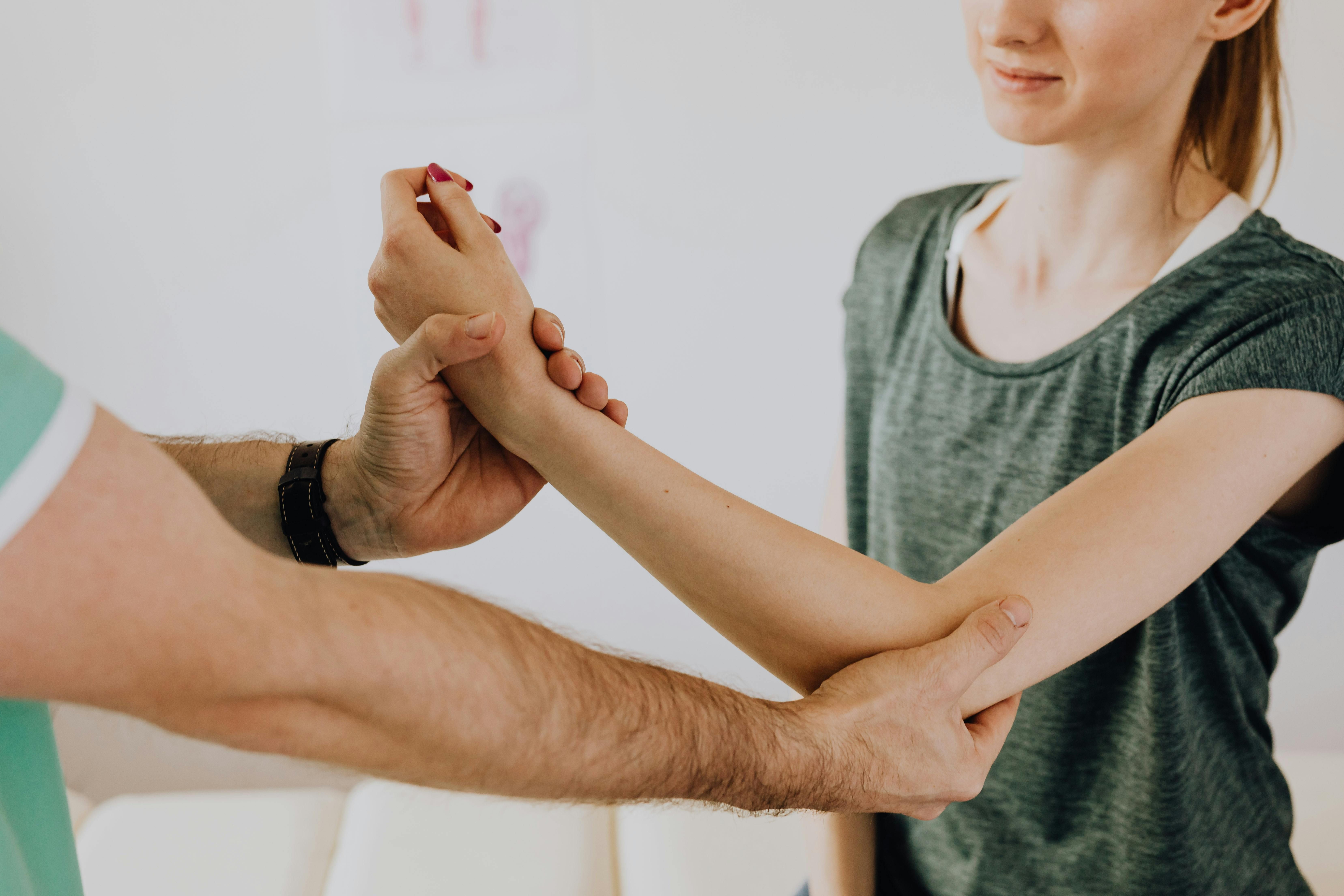 A woman experiencing gout pain in her elbow, holding her arm with a pained expression.