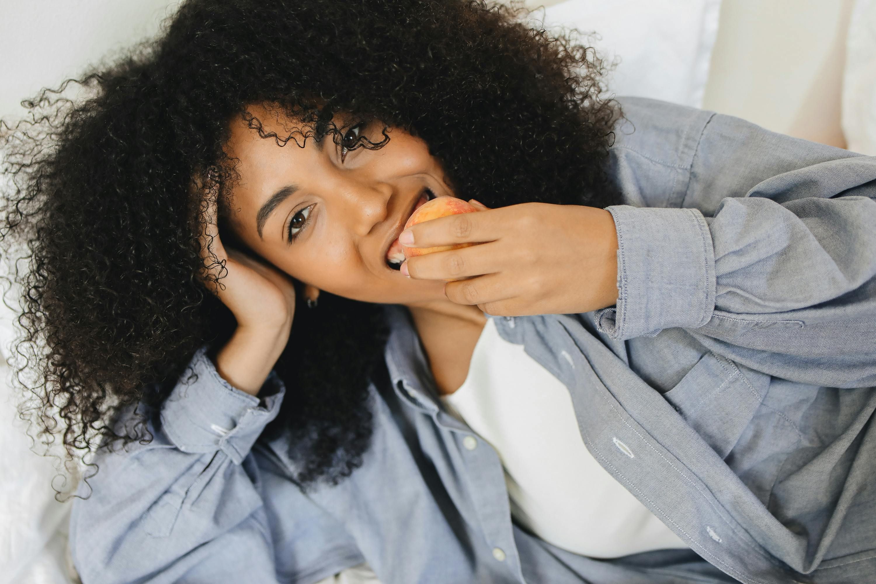 Woman enjoying a peach, incorporating high-fiber fruits into her diet during intermittent fasting